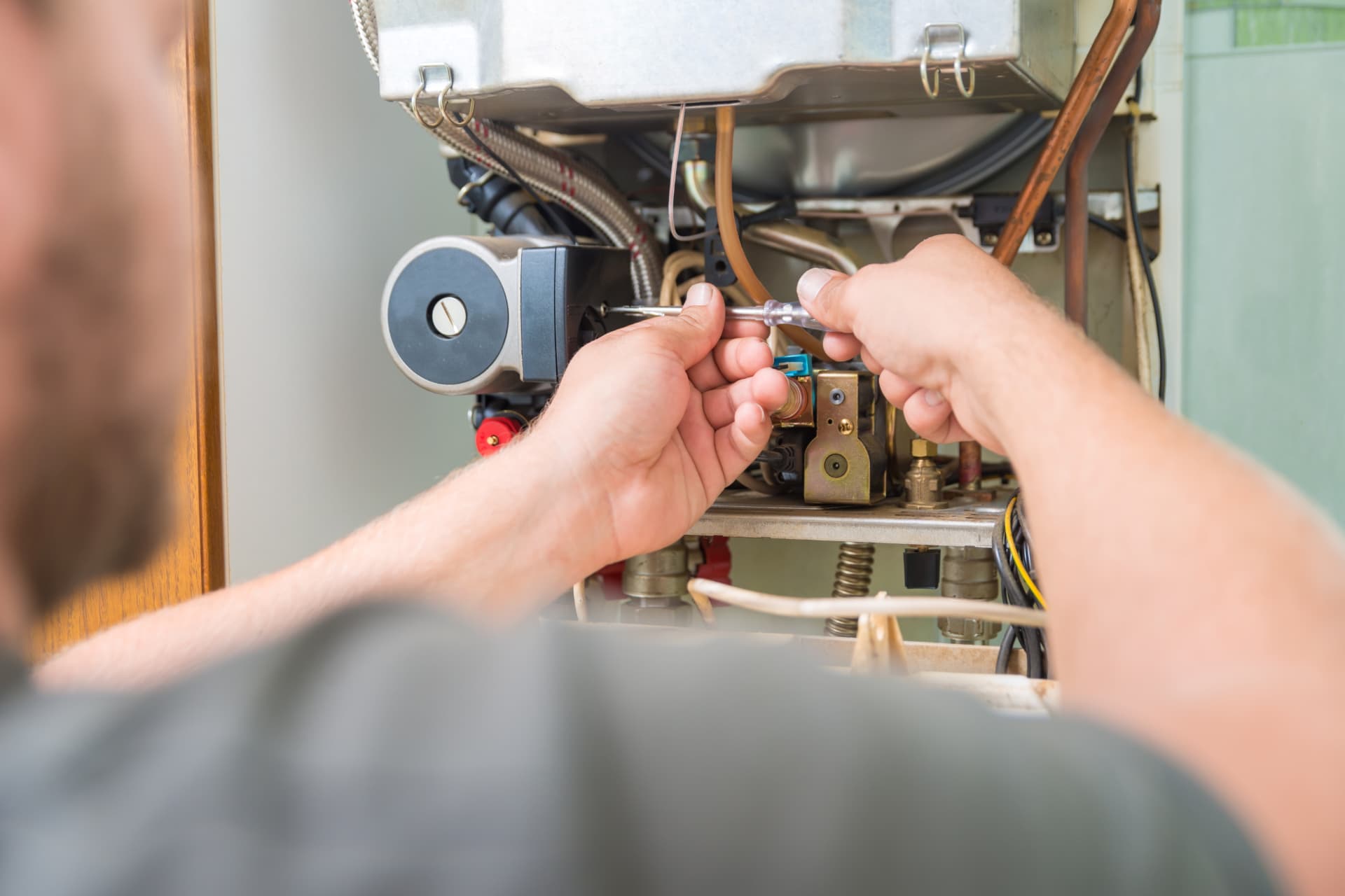 Technician adjusting boiler components during a service